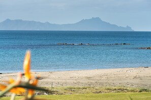 Ein Strand mit freiem Blick auf das Meer und ferne Berge.