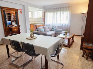 Ein Essbereich mit Tisch, Stühlen und einem Fernseher im Hintergrund.
