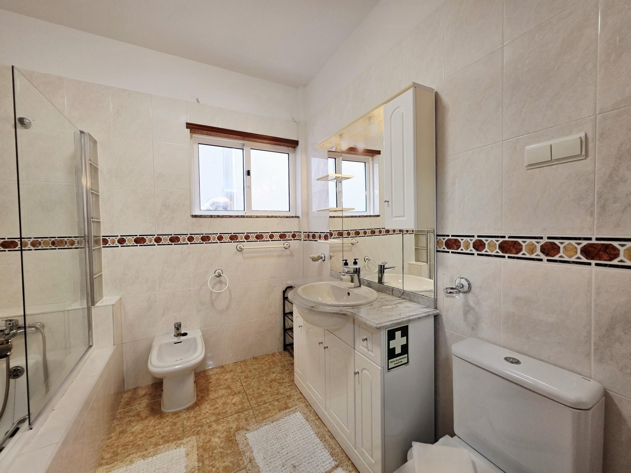 Ein Badezimmer mit Duschkabine aus Glas, einem Bidet, einem Waschbecken, einer Toilette und einem Spiegel.