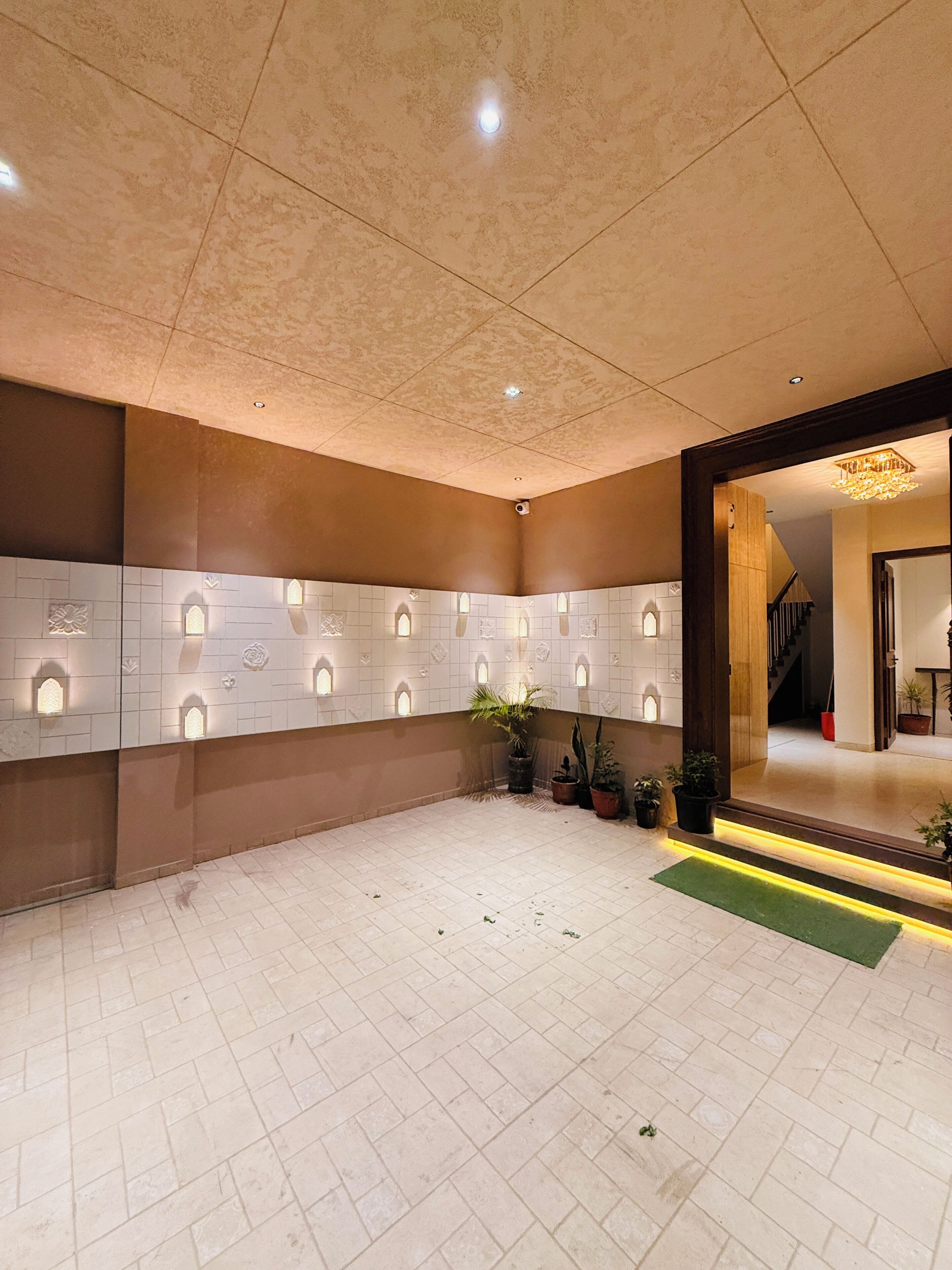 A lobby with a tiled floor, a reception desk with a plant, and a staircase leading to another area.