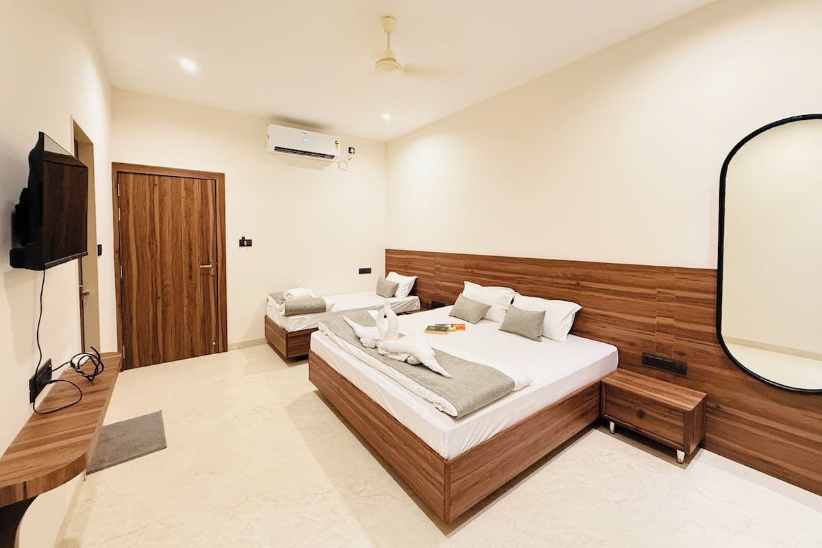 A modern bedroom with a large bed, a wooden headboard, a bedside table, a nightstand, a mirror, and an air conditioning unit.