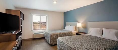 Une chambre d’hôtel avec deux lits, une télévision, une fenêtre donnant sur un paysage agréable et un luminaire au plafond.