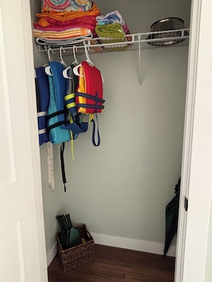 A closet with a shelf holding folded blankets and a rack with life jackets. - Brand New 3-Bedroom Lakefront Home with PICKLEBALL and PONTOON rental option (Cumberland)