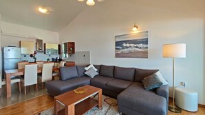 Een woonkamer met een bank, salontafel en een schilderij van een strand.