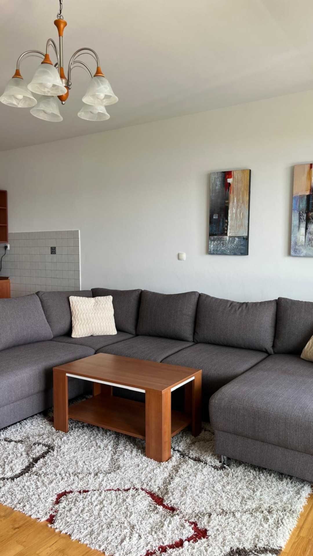 Uma sala de estar moderna com um sofá seccional, uma mesa de centro de madeira e arte abstrata na parede.