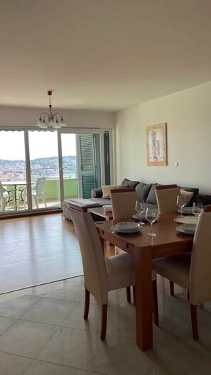 Ein Essbereich mit großem Tisch, Stühlen und Blick durch die Glastüren.