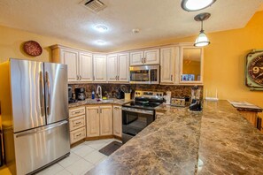 A kitchen with stainless steel appliances, wooden cabinets, a granite countertop, and a clock on the wall. - Sonoran Spa W102 Ground Floor 2BR/2ba (Puerto Peñasco)