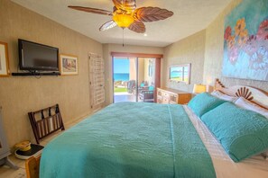 Ein Schlafzimmer mit einem Bett, einem Fernseher, einem Deckenventilator und Meerblick.