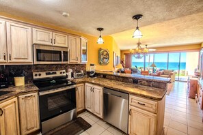 A kitchen with a central island, stainless steel appliances, wooden cabinets, and a view of the ocean. - Sonoran Spa W102 Ground Floor 2BR/2ba (Puerto Peñasco)