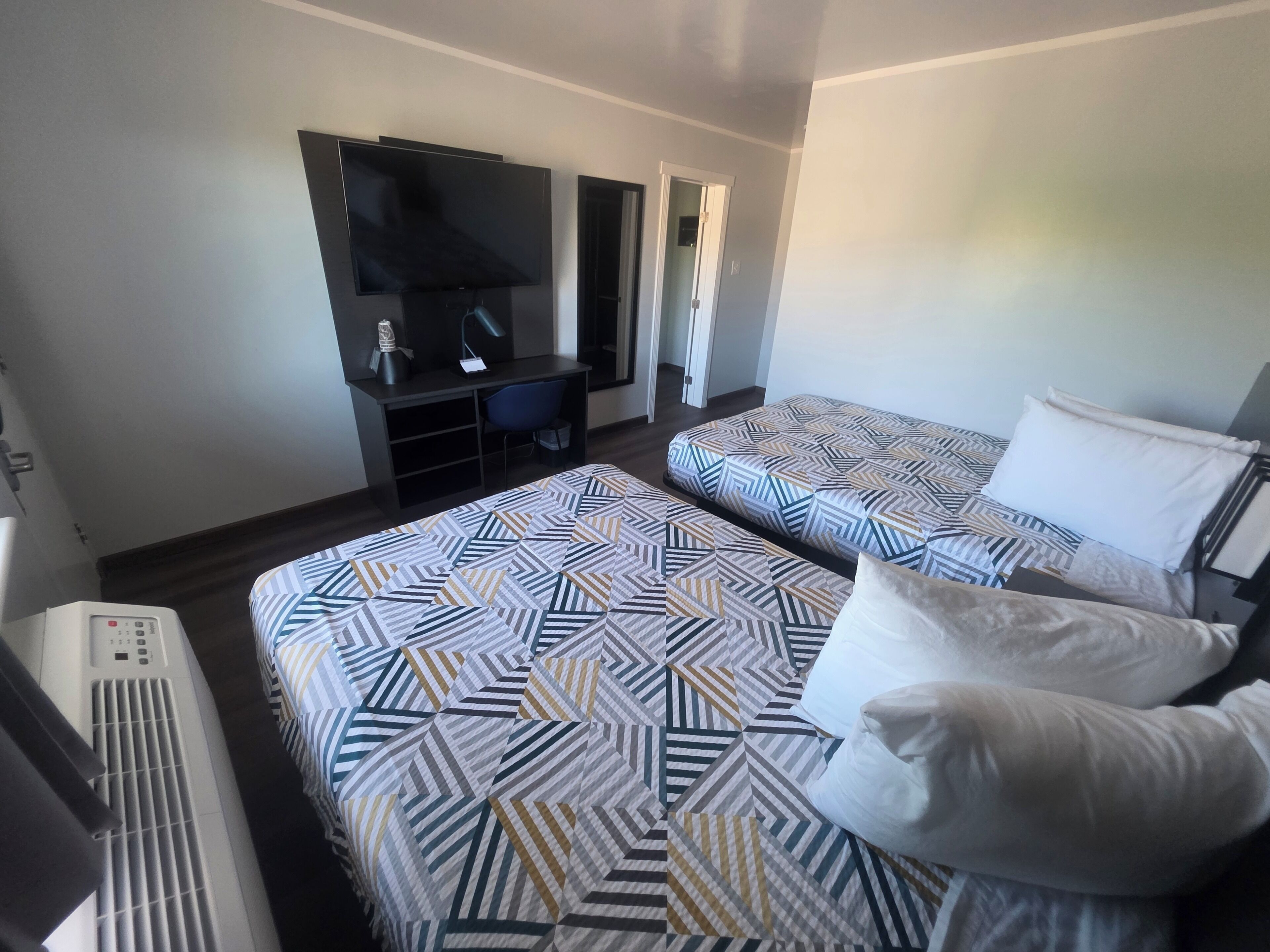 Una habitación de hotel con dos camas, un escritorio, un televisor y un calefactor.