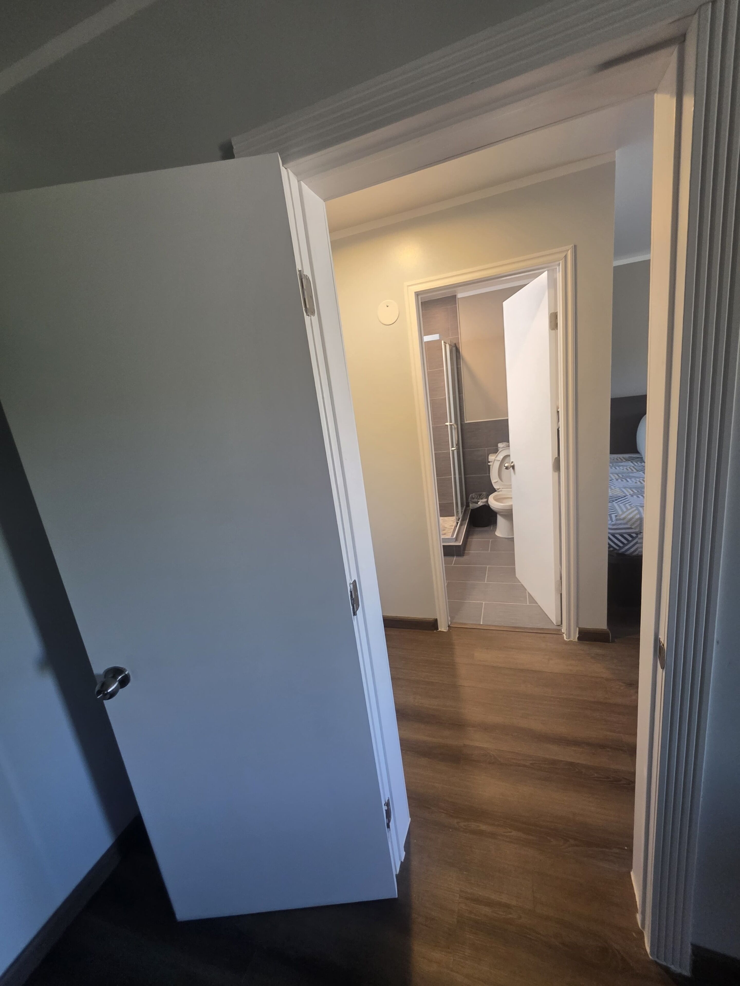 A hallway leading to a bedroom with a bed and a bathroom.