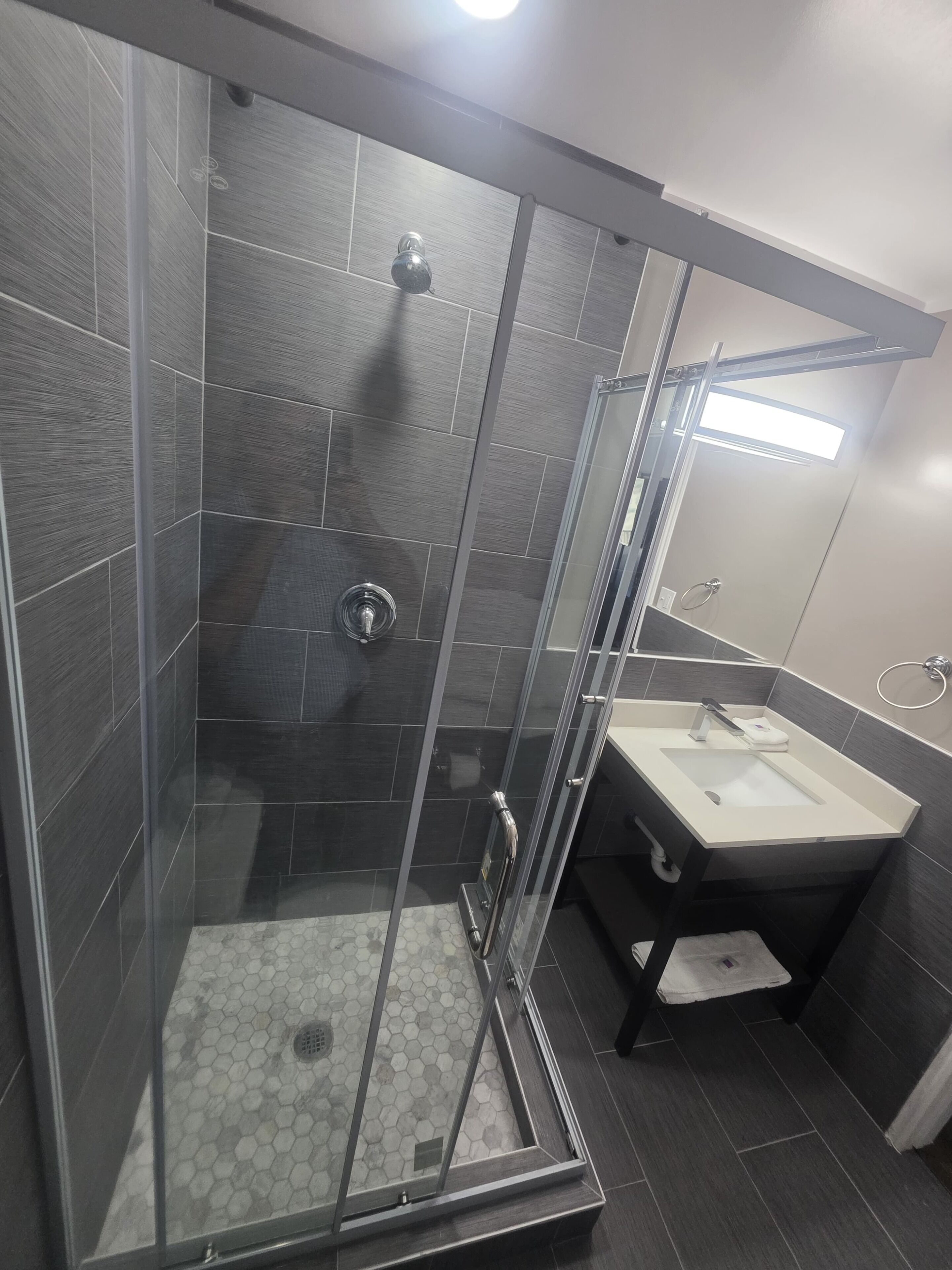 A modern bathroom with a glass-enclosed shower, a sink, and a mirror.