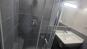 A modern bathroom with a glass-enclosed shower, a sink, and a mirror.