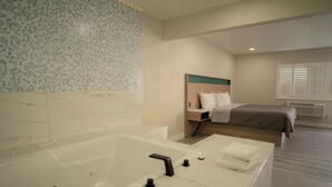 Ein modernes Badezimmer mit einer großen Badewanne, einer Duschkabine und einem Bett mit Holz Kopfteil.