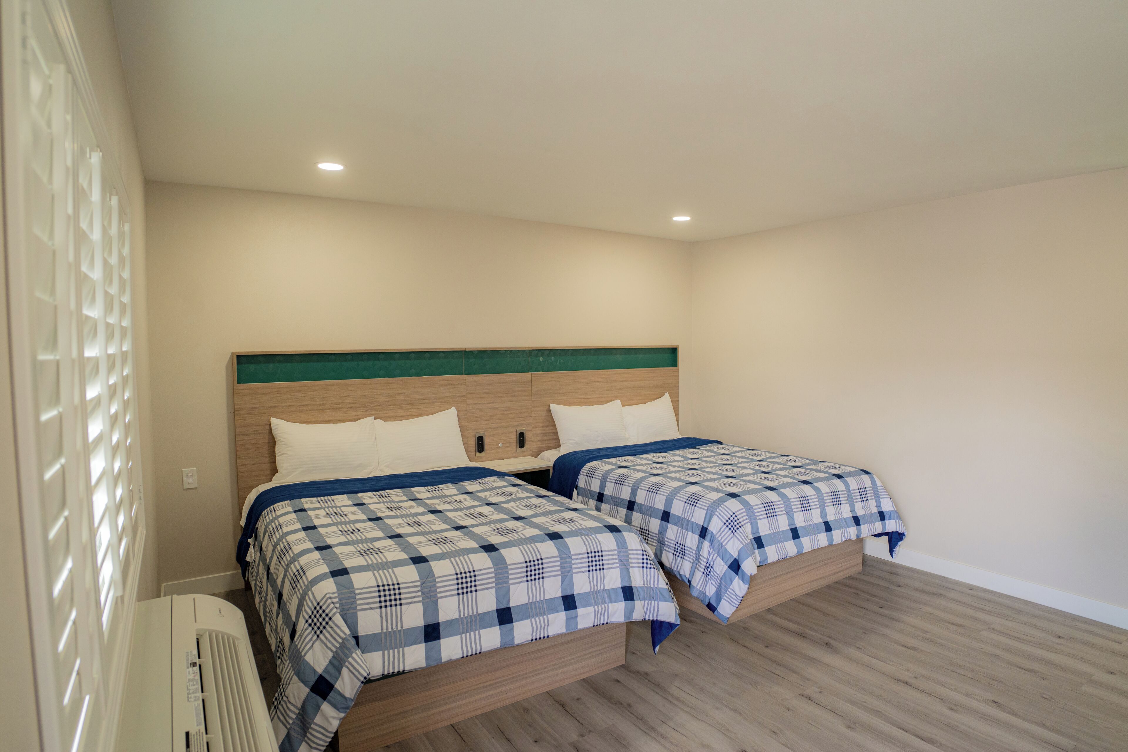 A bedroom with two beds, a wooden headboard, and a white radiator.