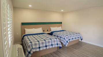 A bedroom with two beds, a wooden headboard, and a white radiator.