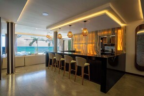 A modern kitchen with a marble backsplash, a bar area with stools, and a view of the ocean. - Villa Magdalena - 7BR - Oceanfront w/ Heated Pool (Cancun)