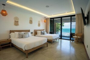 A hotel room with two beds, a TV mounted on the wall, and a large sliding glass door leading to a balcony with a view of the ocean. - Villa Magdalena - 7BR - Oceanfront w/ Heated Pool (Cancun)