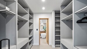Een modern interieur met een centrale gang die leidt naar een badkamer, met open planken en een hangende kapstok.