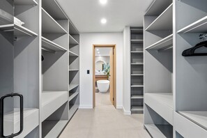 Ein modernes Interieur mit einer zentralen Diele, die zu einem Badezimmer führt, mit offenen Regalen und einer Kleiderstange.