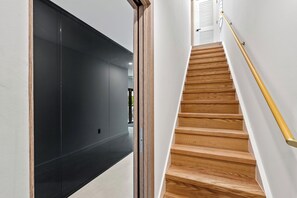 Eine moderne Treppe mit Holzboden und einem gelben Geländer, die zu einem Raum mit schwarzer Wand und weißer Tür führt.