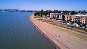 Une zone côtière comprenant une plage, une route et un immeuble à plusieurs étages doté de balcons.