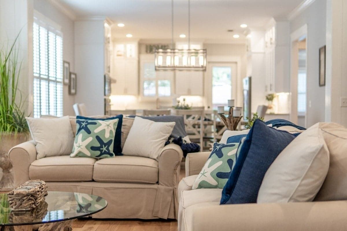 Un salon moderne avec un canapé beige, une table basse en verre et des coussins décoratifs.