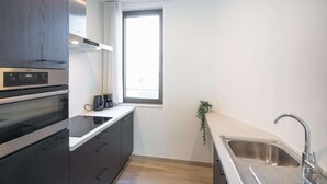Moderni keittiö, jossa on sisäänrakennettu uuni, ikkuna ja pesuallas.