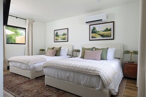 A double room with two beds, a large window, and an air conditioning unit. - Steps from the Lake- Sauna + Hot Tub. Room #4 (Jones)