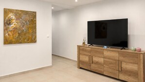 A modern living room with a flat-screen TV, wooden cabinet, and abstract art on the wall. - 1 bedroom cozy apartment in Vir (Vir)