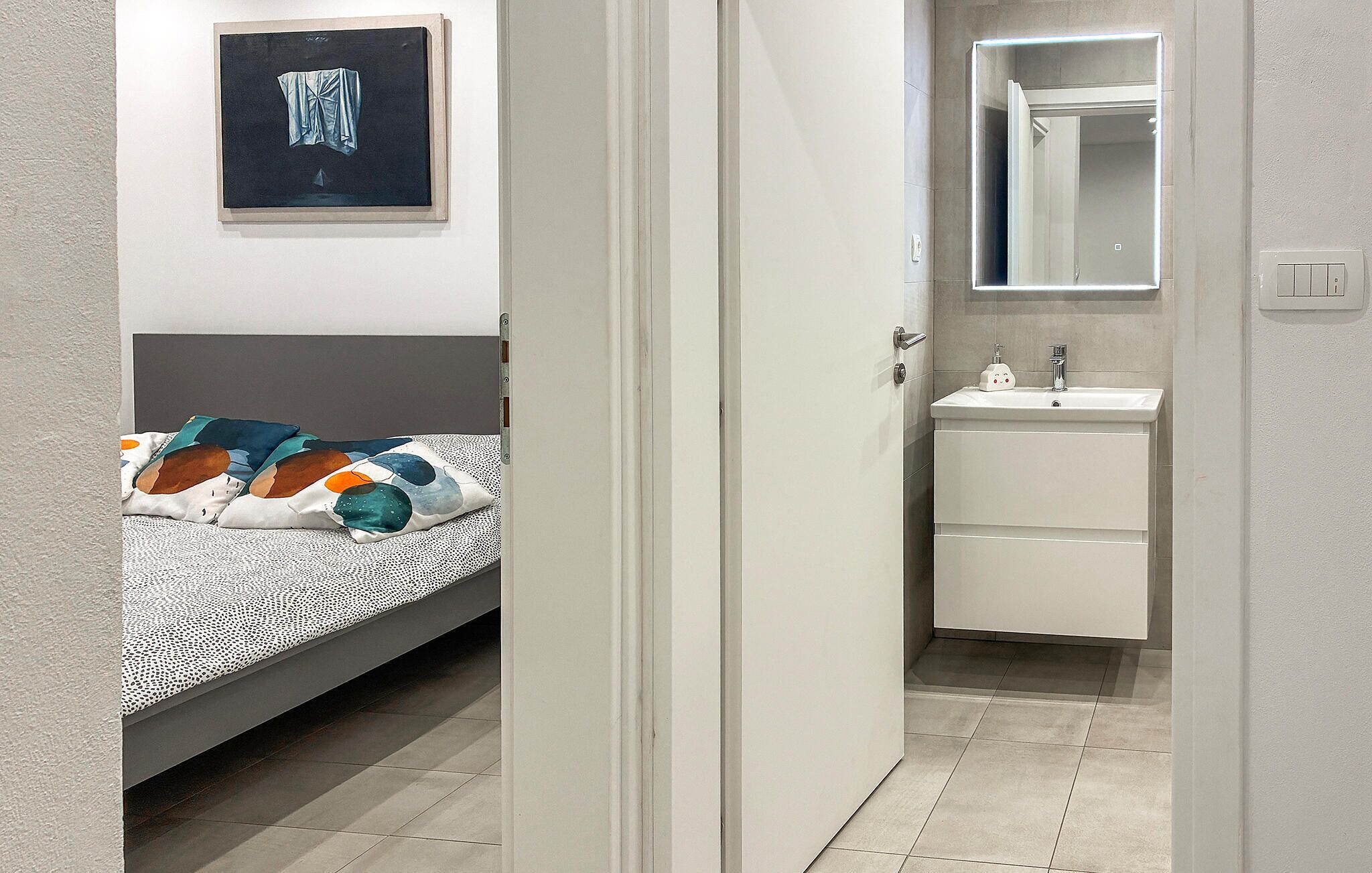 A bedroom with a bed, a bedside table, and a wall-mounted painting.