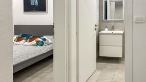 A bedroom with a bed, a bedside table, and a wall-mounted painting. - 1 bedroom cozy apartment in Vir (Vir)