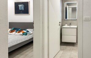 A bedroom with a bed, a bedside table, and a wall-mounted painting. - 1 bedroom cozy apartment in Vir (Vir)