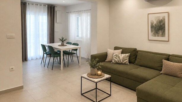 A modern living room with a green sofa, a dining table with chairs, and a small side table with a candle. - 1 bedroom cozy apartment in Vir (Vir)