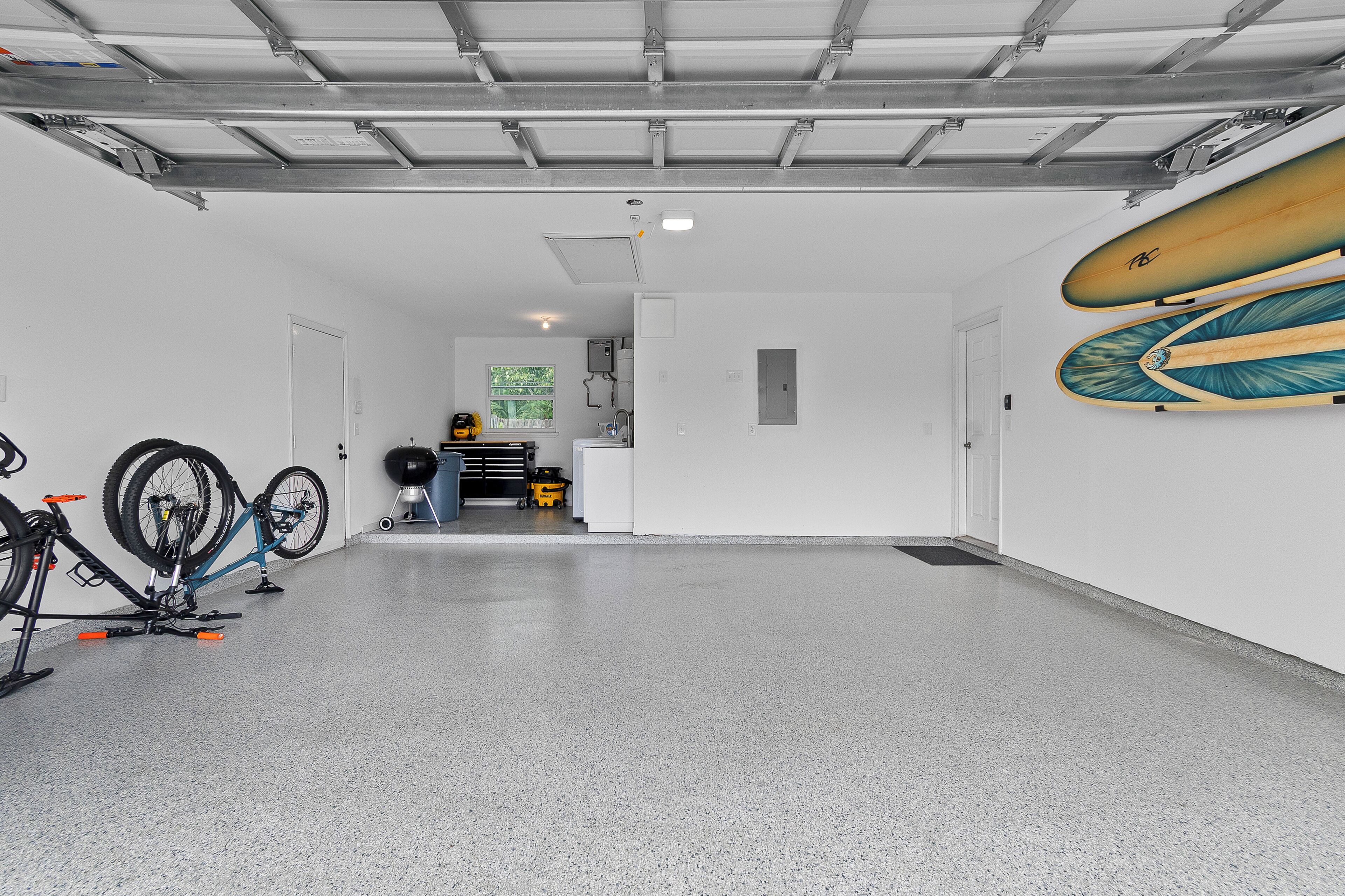 Un garage con due biciclette, una tavola da surf e un portabici.