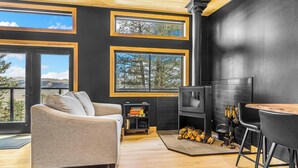 Ein modernes Interieur mit Kamin, großen Fenstern, einer Couch und einer Bar.