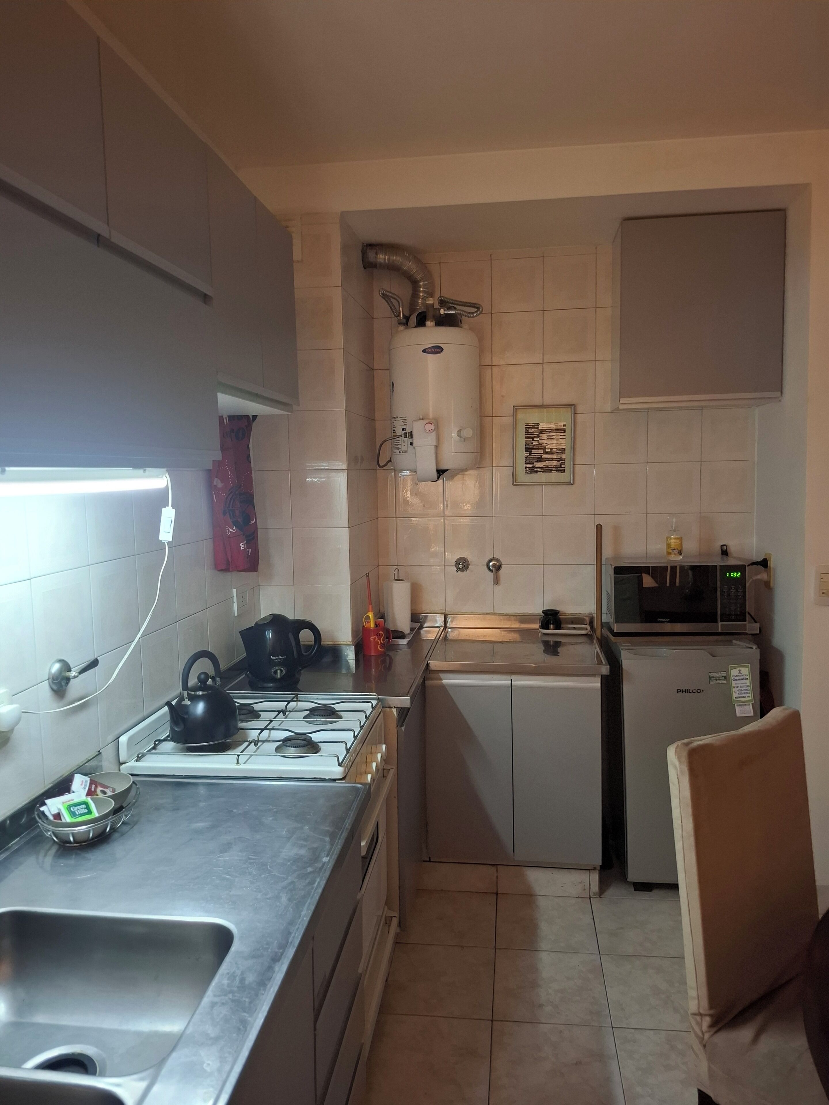 Une cuisine compacte équipée d’une cuisinière à gaz, d’un évier, d’un four à micro-ondes et d’un petit réfrigérateur.