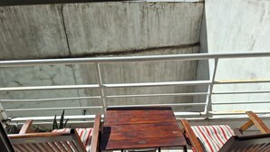 Varanda com mesa de madeira e duas cadeiras estofadas listradas.