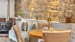 A cozy living room with a stone wall, a round wooden table, and a sofa. - Lake House Staycation (Hollingbourne)