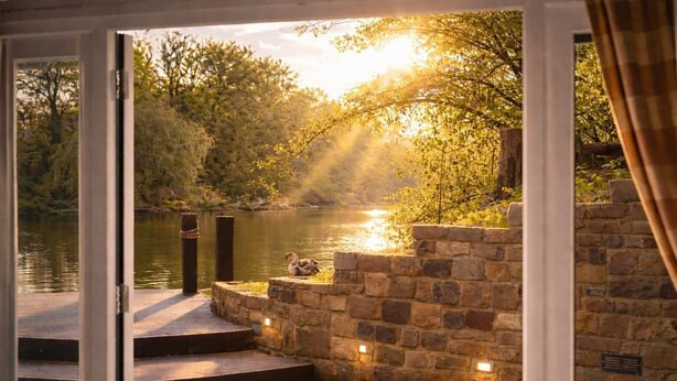 A stone wall with steps leading to a body of water, a swan, and a sunset view. - Lake House Staycation (Hollingbourne)