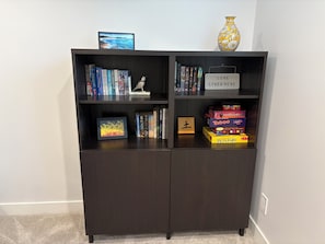 A dark wooden bookshelf with books, a framed picture, a decorative bird, a vase, and a sign saying 'LOVE LIVES HERE'.