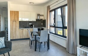 A modern kitchen with white cabinets, a dining area with grey chairs, and a large window with curtains. - Stunning apartment in Maslenica (Maslenica)