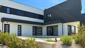 Uma casa moderna de dois andares com piscina, janelas amplas e design minimalista.