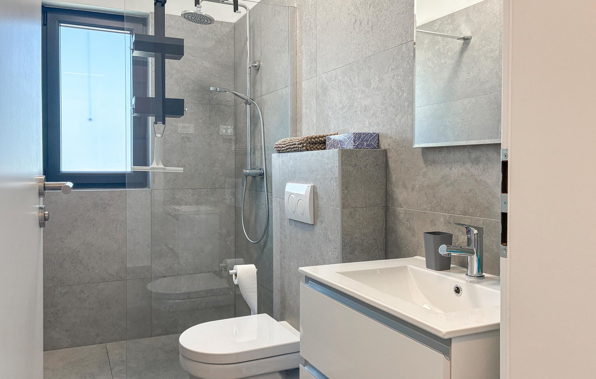 A modern bathroom with a glass shower enclosure, a toilet, a sink, and a towel rack.