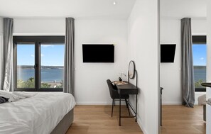 A bedroom with a bed, a desk, a chair, a flat-screen TV, and a view of the sea. - Cozy home in Maslenica (Maslenica)