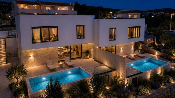 Ett modernt hus i två våningar med en swimmingpool, en uteplats och en fasad av sten.