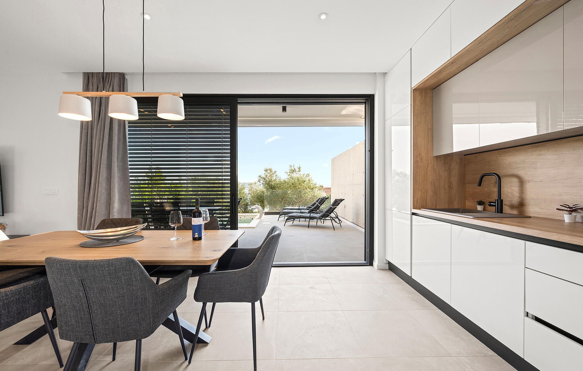 A modern kitchen with a dining area, a view to the outside, and a small plant on the counter.