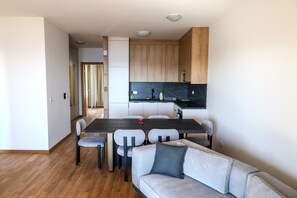 Eine moderne Küche mit Holzausstattung, einer schwarzen Arbeitsplatte und einem Essbereich mit grauem Sofa und Stühlen.
