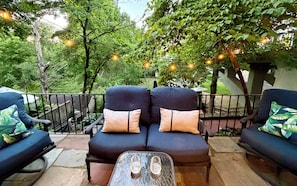 A patio with two black sofas, each with a single cushion, and a small table with two glasses. - Creekstone House • Walk to Town • Hot Tub + Parking (New Hope)