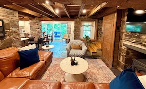 Un interior acogedor con paredes de piedra, un sofá de cuero, un sillón estampado y una chimenea.